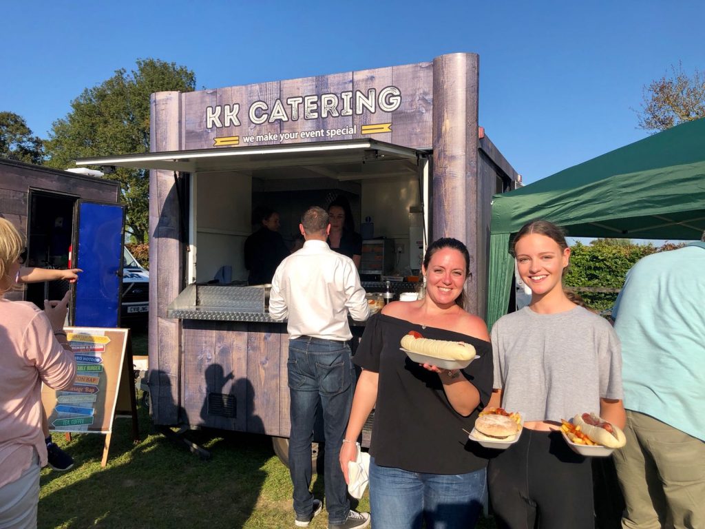 2 women with burger and fries at a kk catering unit
