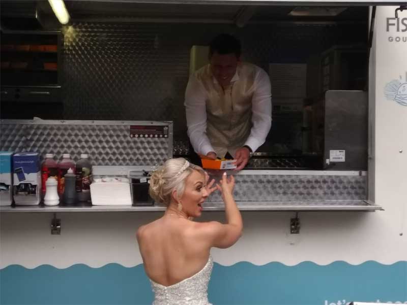 bride being served fish and chip by husband at fish and chip van