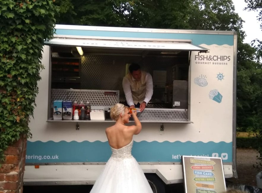 groom serving bride fish and chips from fish and chip van