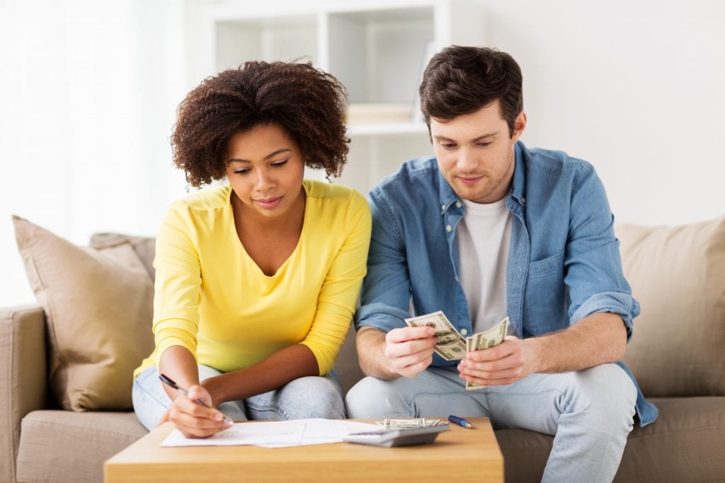family budget, finances and people concept - couple with papers and calculator counting money at home