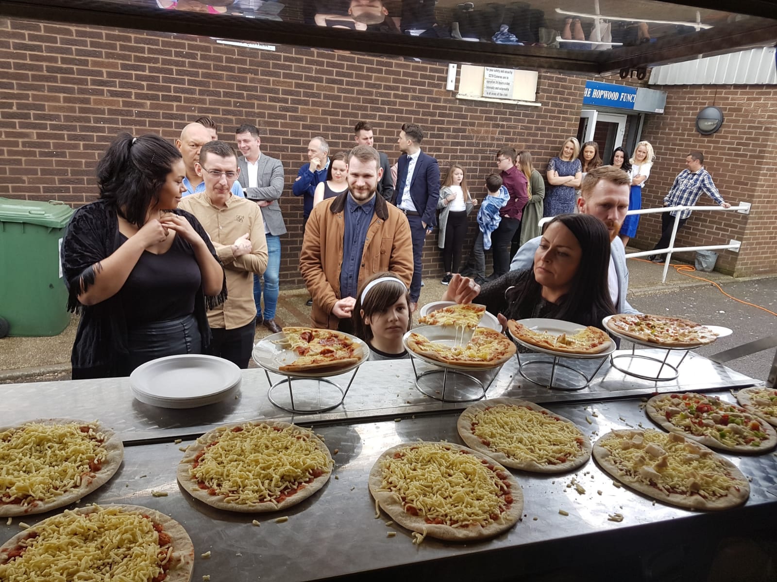 Group of people waiting for pizza at a self service pizza bar