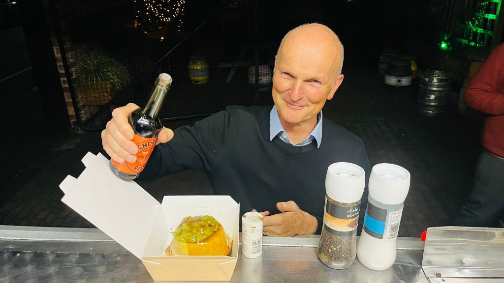 man putting Worcestershire sauce of his kk catering pie mash and peas